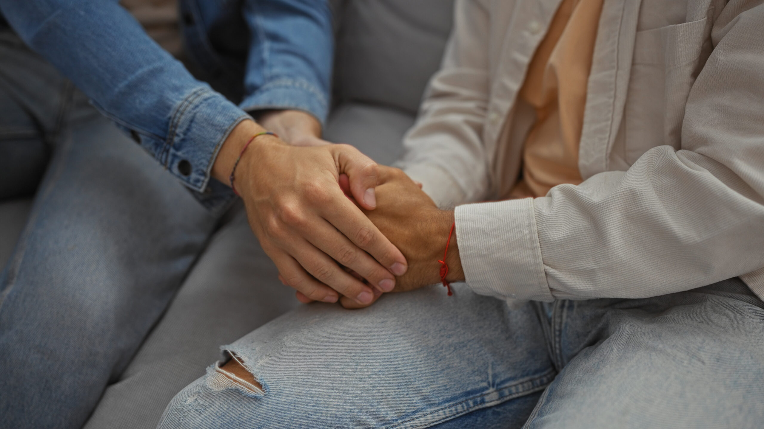 two people on a couch holding hands, no faces are shown