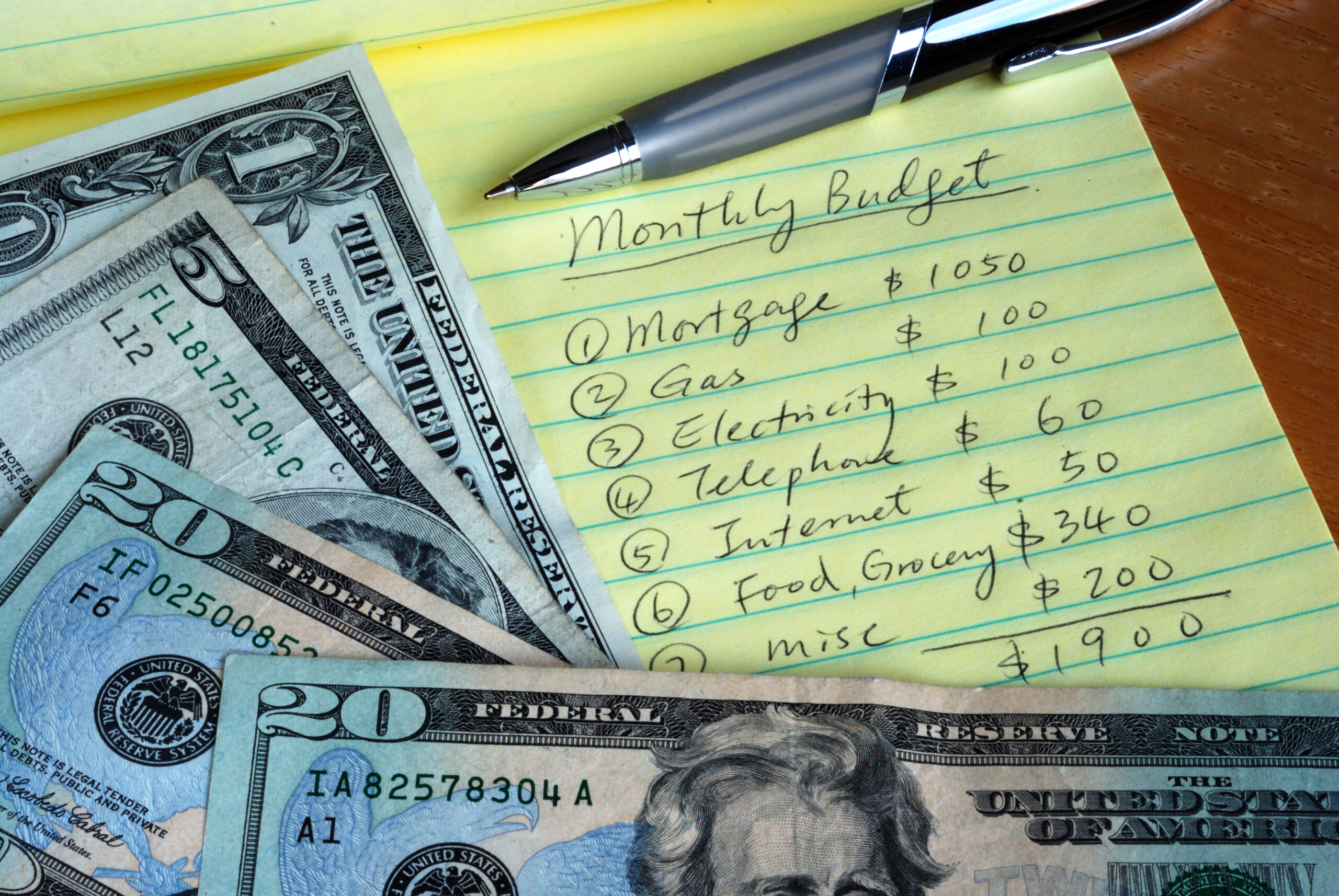 Money stacked on a notepad that includes a monthly budget